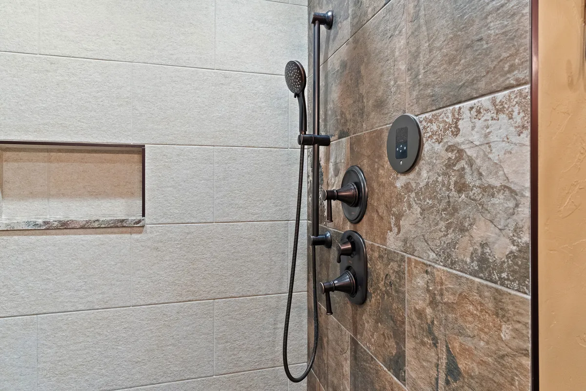 A close-up view of a modern shower with stylish tilework, sleek fixtures, and a rain-style showerhead, evoking a spa-like atmosphere perfect for relaxation and rejuvenation.