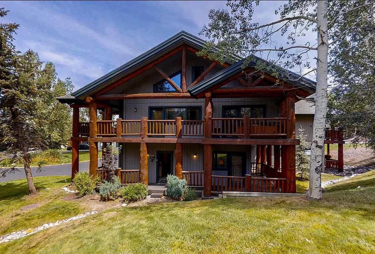 This exterior image showcases a wooden balcony overlooking a stone pathway, surrounded by lush greenery. The scene exudes tranquility, inviting guests to enjoy the outdoors, whether relaxing on the balcony or preparing for a day in the snow.