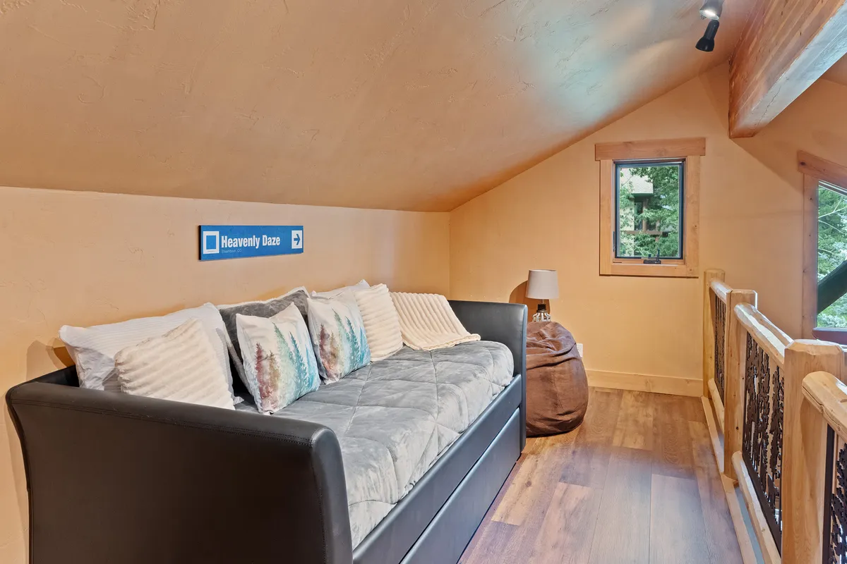 A comfortable living area featuring a plush sofa with decorative pillows, a lamp for reading, and a window offering tranquil views. The ambiance is both inviting and functional, suitable for relaxation or hosting additional guests.