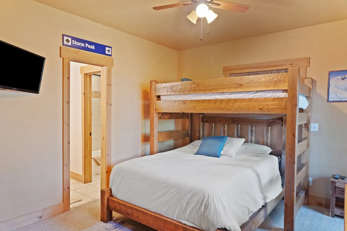 A flexible bedroom featuring a Twin XL over Queen bunk bed, wall art, TV, and a cozy, relaxed atmosphere. The layout invites both comfort and practicality for families or groups of friends.