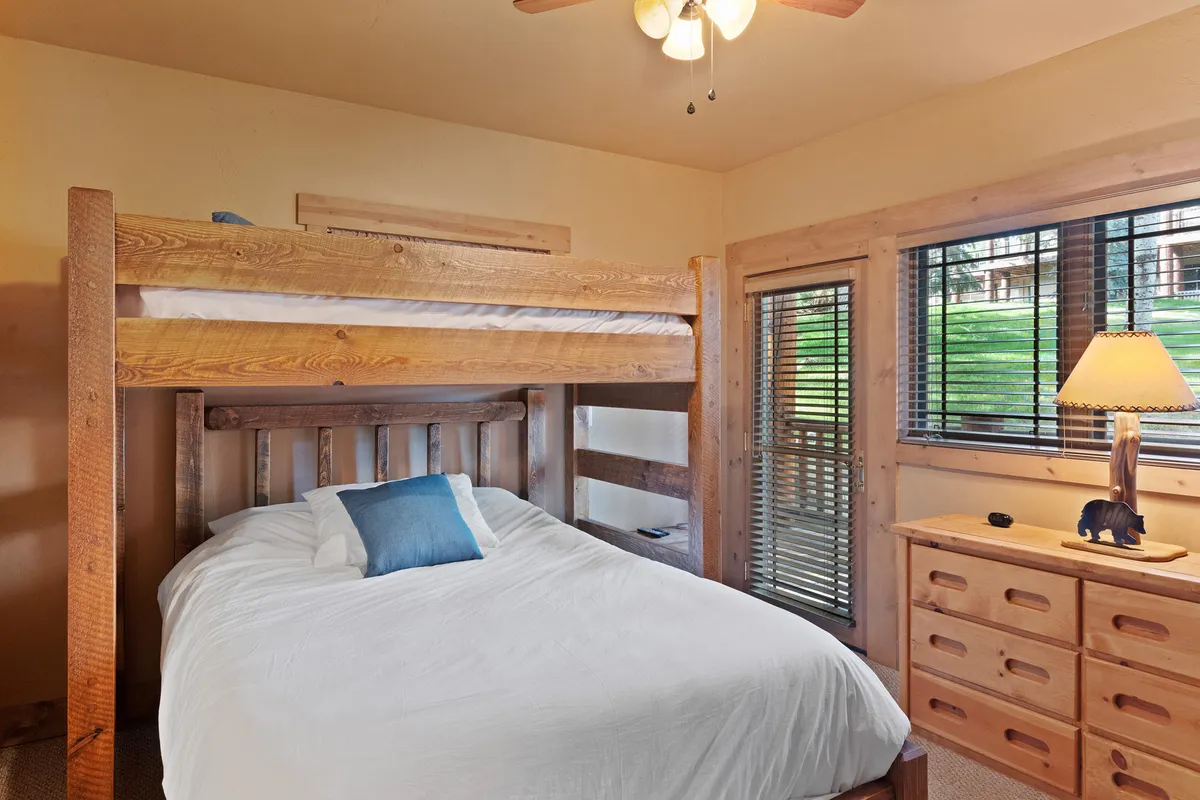 A cozy bedroom setup with a bunk bed, a queen bed, and a nightstand with a lamp, decorated in inviting hues. The space is perfect for children, solo travelers, or guests seeking flexible sleeping arrangements.