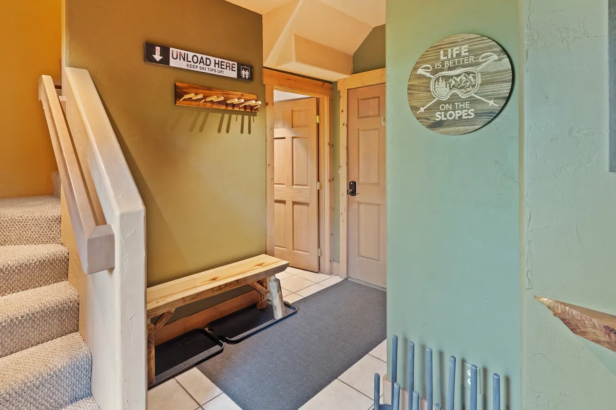 A cozy mudroom with a bench for seating, signage on the wall, and multiple doorways hinting at convenient access to other parts of the home. The space appears inviting and practical, serving as a perfect drop zone for outdoor gear and setting a welcoming tone as soon as you enter.
